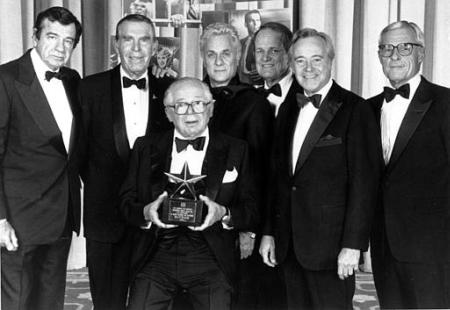 Director, producer, and writer Billy Wilder is shown holding his American Film Institute Life Achievement Award, presented on March 6, 1986. Posing with Wilder are, from left to right: Walter Matthau, Fred MacMurray, Tony Curtis, George Stevens, Jr., and Jack Lemmon, who hosted the AFI event. On the right is Grant A. Tinker, former Chairman and Chief Executive Officer of NBC.