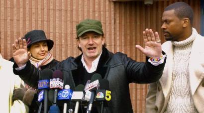 Irish rock star Bono, lead singer of U2, makes a point to a crowd on Chicago's South Side where he talked about the AIDS epidemic in Africa and forgiving third-world debt, Wednesday, Dec. 4, 2002. The stop was one of several of his seven-day bus tour through seven Midwestern states to raise awareness of the epidemic in Africa. Bono is joined by actress Ashely Judd, left, and comedian Chris Rock, right. Photo by Charles Bennett