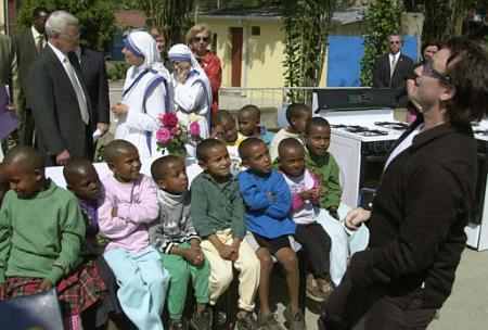 Irish rock star Bono right, from the band U2, jokes with HIV/AIDS children at Missionaries of Charity AIDS hospice in Addis Ababa, Ethiopia, Thursday May 30, 2002. At left standing is U.S. Treaury Secretary Paul O'Neill, talking to Sister Benedicta, middle. O'Neill presented a check for U.S. dlrs 400,000 to the Missionary. Bono and O'Neill met with Ethiopian religious leaders on HIV/AIDS.  Photo by Sayyid Azim