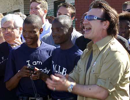 Bono sings his band U2's song 'I Still Haven't Found What I'm Looking For' after being greeted by dancing schoolchildren near Soweto, South Africa, May 24, 2002. Photo by Juda Ngwenya