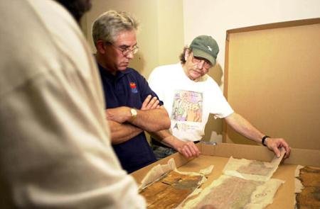 C. Wesley Cowan of Cowan's Historic Americana Auctions, left, looks, June 21, 2002, at a 1878 Buffalo Bill Cody billboard found behind a brick wall on a downtown Jamestown, N.Y., building. The 26-by-10 billboard was uncovered when workers began removing the wall last month to prevent it from collapsing. Also pictured is Mike Flaxman, right, board member of the Arts Council for Chautauqua County. Photo by Joe R. Liuzzo