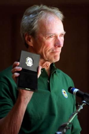 Clint Eastwood jokes while showing his new California Parks and Recreation Commission badge to the crowd Saturday, June 8, 2002, at Big Basin State Park in Boulder Creek, Calif. Eastwood was on hand for a ceremony celebrating Big Basin's 100th anniversary during which he took the oath as the state's newest parks commissioner. Big Basin is California's oldest state park. Photo by Shmuel Thaler