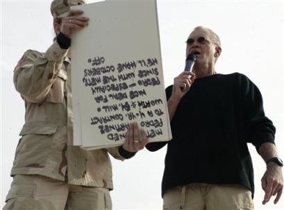 In this picture released by the U.S. Marines, an Army soldier holds up cue cards as comedian David Letterman delivers his opening monologue written specifically for the troops during 'The Late Show' at Camp Taqaddum, Iraq, on Friday, Dec. 24, 2004. Letterman, along with his musical director Paul Shaffer and stage manager Biff Henderson, brought the popular late night television show to the Marines, sailors and soldiers currently stationed at Camp Taqaddum, Iraq.  Photo by Sgt. Luis R. Agostini