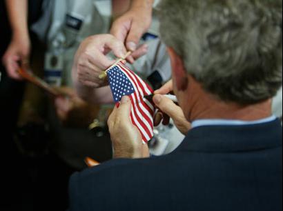 Resident Bush signs American flags for workers at Beaver Aerospace and Defense after speaking about jobs and economic growth in Livonia, Michigan, Thursday, July 23, 2003. President Bush, in campaign-style speeches in states vital to his re-election, sought Thursday to make sure voters give him credit for rebates heading to millions of taxpayers this week. Photo by Charles Dharapak