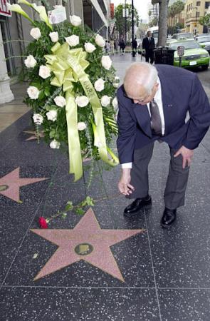 Johnny Grant, the Honorary Major of Hollywood, places a rose on the Walk of Fame's Star of Dudley Moore. Photo by Nick Ut