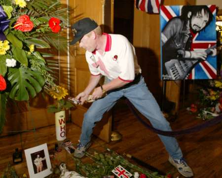 Pat Currie of Salem Township, Michigan places a pack of Winston cigarettes at a memorial for 