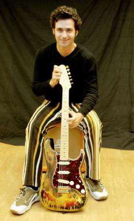 Dweezil Zappa, son of legendary rock musician Frank Zappa, sits with the Fender Stratocaster guitar that was owned by and burned on stage by Jimi Hendrix at the 1968 Miami Pop Festival, before its auction in London August 27, 2002. The guitar, which was given to Frank Zappa by Hendrix after the performance, is due to be auctioned at Cooper Owen on September 24 where, if it achieves its expected sale of 350-400,000 pounds ($532-608,000), it will be the most expensive guitar ever sold. Photo by Ian Waldie