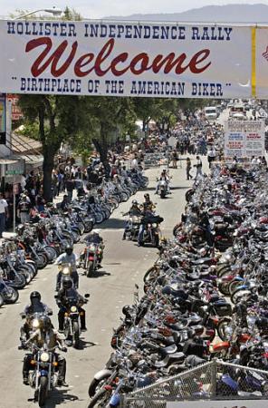 Motorcyclists cruise in front of thousands of parked motorcycles on the main street of Hollister, Calif., during the Hollister Independence Rally, Saturday, July 6, 2002. Tens of thousands of motorcycle fans jammed into this sleepy farm town for a Fourth of July holiday weekend rally. Photo by Paul Sakuma