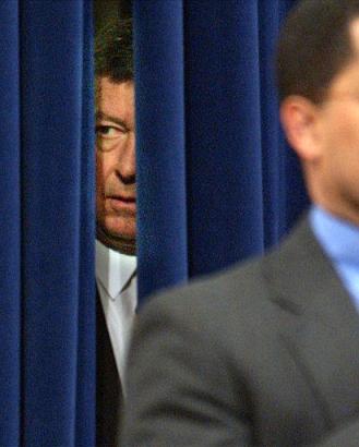 Attorney General John Ashcroft peeks out from behind the curtain before his speech as Assistant Attorney General for the Civil Rights Division Ralph Boyd, partially seen at right, participates in a ceremony with Justice Department employees in honor of the legacy of Martin Luther King, Jr. Friday, Jan. 17, 2003 in Washington. Photo by Evan Vucci