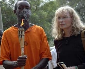 UNICEF goodwill ambassador U.S. actress Mia Farrow walks together with an unidentified Rwandan genocide survivor as they relay a symbolic torch in front of a mass grave at the Ecole Technique Officielle in Kigali August 15, 2007. Farrow and fellow campaigners have begun an Olympic-style torch relay through countries that have suffered genocide to press China to help end abuses in the Darfur region of its ally Sudan.  Photo by Arthur Asiimwe