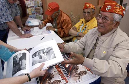 Navajo Code Talker Bill Toledo smiles while accepting a book on Code Talkers so that he can sign a picture of himself during an autograph session at the Indian Pueblo Cultural Center in Albuquerque, N.M., on April 22, 2002, featuring Toledo and fellow Code Talkers John Brown, middle, and Chester Nez, left. Five elderly Navajo men are the only survivors of the elite group, to whom many credit the Allied victory over Japan. Photo by Jake Schoellkopf