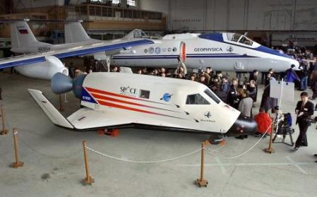 Journalists work near a life-sized mock-up of S-XXI space ship, foreground, as M-55 carrier aircraft stands behind it at an air base in Zhukovsky, near Moscow, Thursday, March 14, 2002. Photo by Ivan Sekretarev